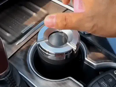 Cenicero vehicular con tapa giratoria en uso